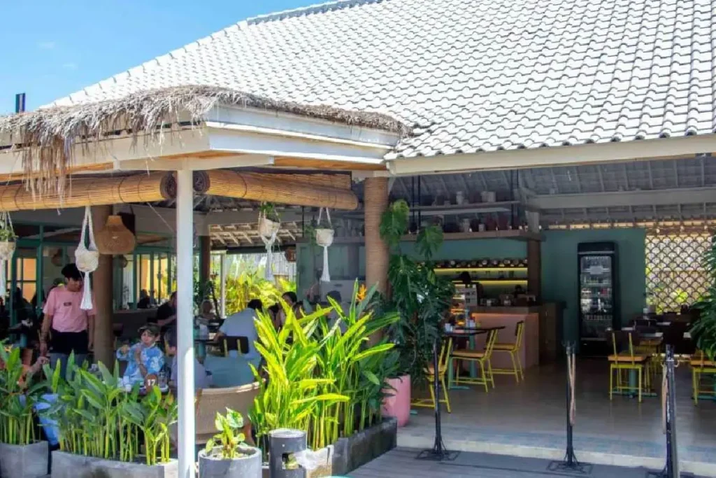 Interior of a cozy modern warung in Uluwatu with plants, iced tea, and a rice plate - travel photo