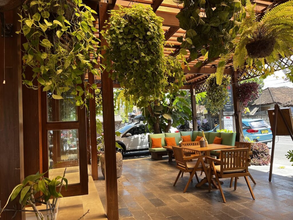 Garden-style warung seating with buffet counter and banana leaves - travel photo
